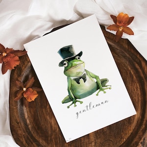 May include: A watercolor illustration of a green frog wearing a black top hat and a bow tie. The frog is sitting on a white background with the word "gentleman" written below it.