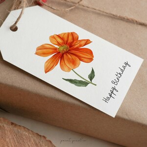 K&ouml;nnte beinhalten: Ein wei&szlig;er Geschenkanh&auml;nger mit einer Illustration einer orangefarbenen Blume und dem Text "Happy Birthday".