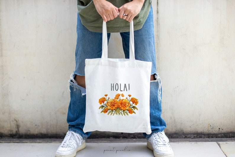 May include: A white tote bag with the word "HOLAI" printed in black and a floral design featuring orange marigolds.