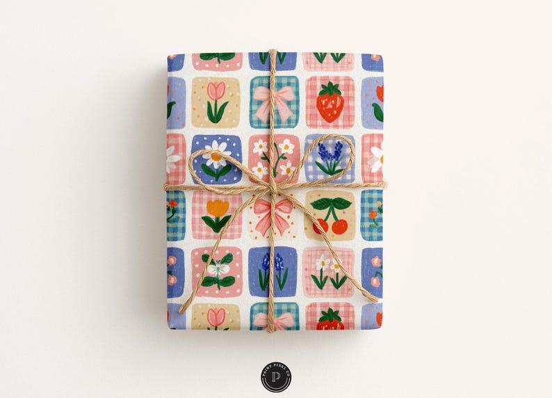 Puede incluir: Un regalo rectangular envuelto en papel con una cuadr&iacute;cula de cuadrados con ilustraciones de lazos rosas, fresas rojas, cerezas y varias flores, incluyendo tulipanes y margaritas, atado con un cordel marr&oacute;n fino en forma de lazo.