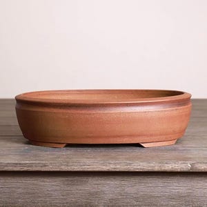 May include: A set of three ceramic nesting bowls in graduating sizes. The bowls feature a speckled, matte finish in shades of cream, light gray, and dark gray. Each bowl has a rounded shape and a slightly flared rim.