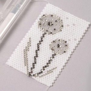 May include: A white beaded bracelet with a silver dandelion design.
