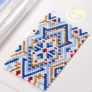 May include: A close-up of a beaded bracelet with a geometric pattern in blue, white, gold, and red.