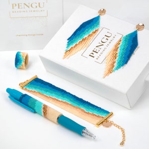 May include: A set of beaded jewelry in shades of blue, beige, and gold. The set includes a bracelet, a ring, a pair of earrings, and a pen. The jewelry is packaged in a white box with the brand name "PENGU BEADING JEWELRY" printed on it. The text "charming things inside" is also printed on the box.