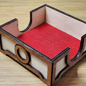 Puede incluir: Una caja de madera con un forro de fieltro rojo. La caja tiene un dise&ntilde;o decorativo en la parte delantera y los lados.