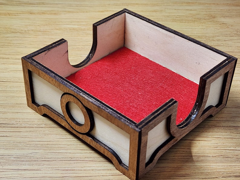 Puede incluir: Una caja de madera con un forro de fieltro rojo. La caja tiene un dise&ntilde;o decorativo en la parte delantera y los lados.