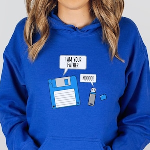 May include: Royal blue hoodie with a graphic of a floppy disk saying "I AM YOUR FATHER" and a USB drive saying "NOOOO!". The hoodie has a kangaroo pocket and a drawstring hood. The design is a humorous take on a classic movie scene.