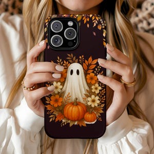 May include: A black phone case featuring a Halloween-themed design. The case showcases a white ghost, orange pumpkins, and autumn leaves and flowers. The design is set against a dark background.