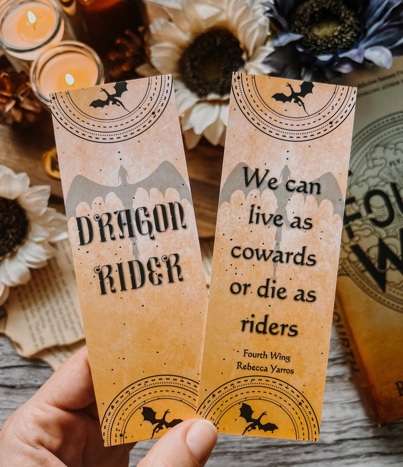 May include: Two yellow bookmark designs with black dragon silhouettes and text. The first bookmark says "DRAGON RIDER". The second bookmark says "We can live as cowards or die as riders - Fourth Wing Rebecca Yarros".