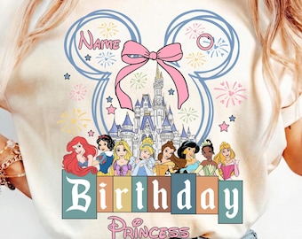 May include: Cream-colored t-shirt featuring a Disney-themed design. The design includes a castle, princesses, a pink bow, and the words "Birthday Princess". The shirt has a Mickey Mouse ear outline with the word "Name" inside.