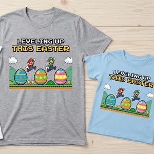 May include: Three t-shirts with the text "Leveling Up This Easter" and a graphic of Mario and Luigi jumping over Easter eggs. The shirts are white, gray, and light blue.