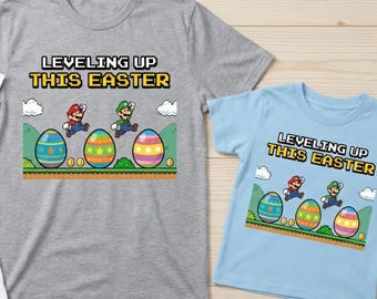 May include: Three t-shirts with the text "Leveling Up This Easter" and a graphic of Mario and Luigi jumping over Easter eggs. The shirts are white, gray, and light blue.