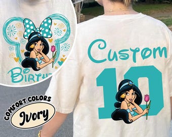 May include: Ivory long-sleeve t-shirt featuring a teal Minnie Mouse-inspired design with Princess Jasmine holding a pink tulip. The back of the shirt has the word "Custom" and the number "10" with a Jasmine graphic.