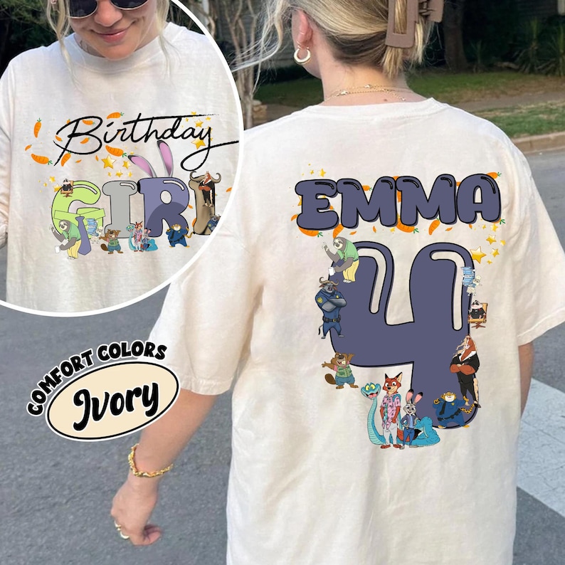 K&ouml;nnte beinhalten: Elfenbeinfarbenes T-Shirt mit dem Text "Birthday Girl" und einer Cartoon-Grafik auf der Vorderseite. Auf der R&uuml;ckseite des Shirts steht der Name "EMMA" &uuml;ber der Zahl "4" mit Cartoon-Figuren. Das Shirt ist von der Marke Comfort Colors.