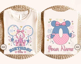 May include: Off-white t-shirt with a front design featuring a pink castle, a pink bow, and the text "BIRTHDAY GIRL". The back design has a blue zero with a pink polka-dotted bottom, a pink bow, and the text "YOUR NAME".