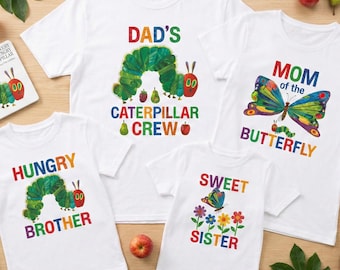 May include: White t-shirts with colorful graphics. One says "DAD'S CATERPILLAR CREW", another "MOM of the BUTTERFLY", and others "HUNGRY BROTHER" and "SWEET SISTER". The designs feature a caterpillar and a butterfly.