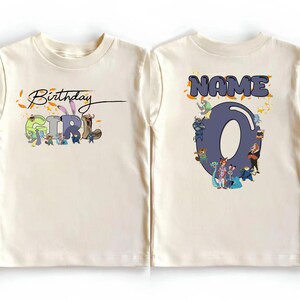K&ouml;nnte beinhalten: Cremefarbenes Kleinkind-T-Shirt mit einer bunten Grafik. Auf der Vorderseite steht "Birthday GIRL" mit Zeichentrickfiguren. Auf der R&uuml;ckseite steht "NAME" &uuml;ber einer gro&szlig;en Zahl "0" mit weiteren Zeichentrickfiguren. Ein lustiges Geburtstags-Shirt.