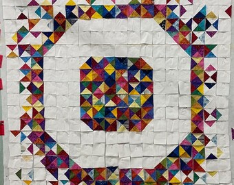 May include: A white background with a colorful patchwork quilt design. The quilt is made up of small squares, each with a different pattern of triangles. The triangles are in various colors, including red, blue, green, yellow, and purple.