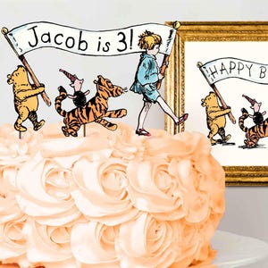 Puede incluir: Un pastel de cumplea&ntilde;os con tem&aacute;tica de Winnie the Pooh con una pancarta que dice "&iexcl;Jacob tiene 3 a&ntilde;os!" y una foto enmarcada de Winnie the Pooh y sus amigos con una pancarta que dice "Feliz cumplea&ntilde;os".