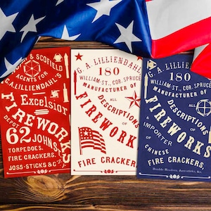 May include: Three vintage-style fireworks advertisements in red, cream, and blue, with patriotic imagery and text. The ads feature the text "Fireworks" and "Fire Crackers" with illustrations of flags and stars. An American flag is draped in the background.