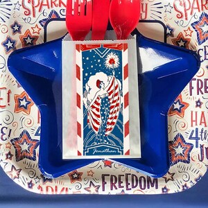 Peut inclure: Une assiette en forme d'&eacute;toile bleue avec une serviette en papier blanche illustrant une femme tenant un drapeau aux couleurs rouge, blanc et bleu. La serviette porte le texte "Jonathan" en bas. L'assiette est sur un fond blanc avec un motif de &eacute;toiles et de feux d'artifice rouge, blanc et bleu.