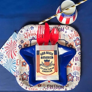 May include: A red, white, and blue themed party plate with a blue star-shaped plate on top. The plate features the text "God Bless America" and "It's Great to Be an American".