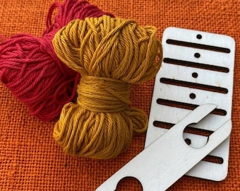 Könnte beinhalten: Ein Bündel rotes Garn, ein Bündel senfgelbes Garn, ein rechteckiges Webwerkzeug aus Holz mit mehreren horizontalen Schlitzen und kleinen runden Löchern sowie ein flaches, helles Holzschiffchen mit einer U-förmigen Aussparung an beiden Enden.