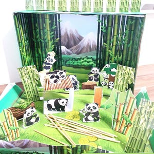 May include: A diorama featuring a panda theme. The scene includes paper cutouts of pandas, bamboo, and mountains. The diorama is set on a green base with the text "PANDA DIORAMA DİJİTAL DIORAMA".