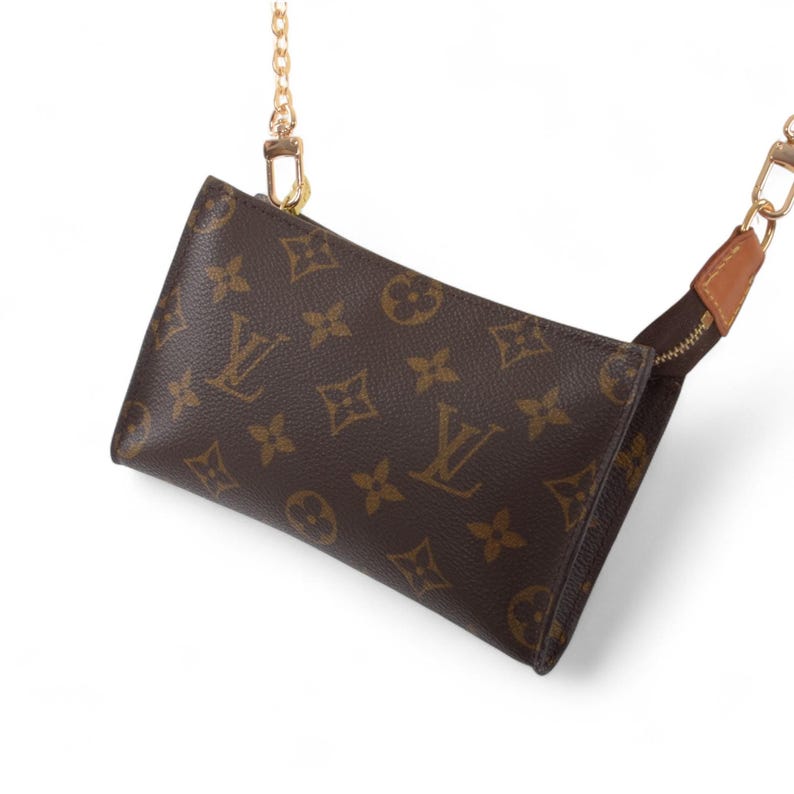 May include: Brown leather crossbody bag with a repeating logo pattern and gold-tone chain strap. The bag features a zipper closure and a small leather accent on the strap. The bag is a classic design.