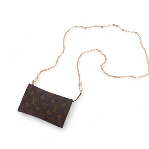 May include: A brown pouch-style bag with a gold chain strap. The bag features a repeating pattern of brown logos on a brown background. The gold chain is long and thin, suitable for wearing the bag as a crossbody.