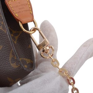 May include: Brown monogram canvas pouch with gold-tone hardware, including a chain strap and clasp. The pouch features a leather accent with the brand name. The design is classic and elegant.