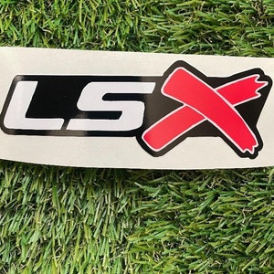 May include: A white sticker with black lettering that reads "LSX" and a red X with a distressed look.