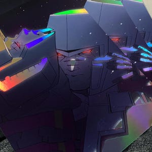 May include: A holographic print of a robot with a metallic blue, purple, and green color scheme. The robot's face is visible and has red eyes. The background is black with a few white stars.