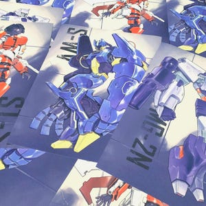 Op de afbeelding: Een assortiment kleurrijke robotillustraties op papier. De robots worden afgebeeld in verschillende poses en kleurenschema's, waaronder blauw, rood, wit en geel. Sommige illustraties hebben tekst, zoals "AM-S" en "MG-ZN".