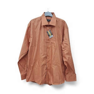 以下が含まれることがあります： 襟付きのオレンジ色の長袖ボタンダウンシャツ。シャツにはタグが付けられています。