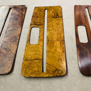 May include: Three wooden panels with different wood grain patterns. Each panel has a rectangular cutout in the center and a long, narrow cutout running vertically down the center.