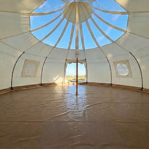 Spacious interior of the glamping tent with an outer wall height of 5 feet expaning to over 10 feet in the middle. Multiple windows, a stove jack, a large door, and a stunning transparent skylight offering beautiful views of the sky.