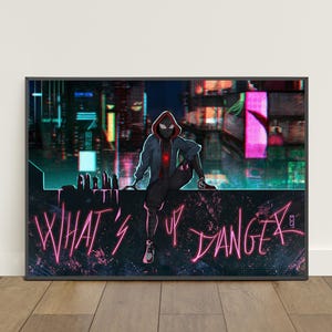 Pu&ograve; includere: Stampa artistica incorniciata con un personaggio in tuta con cappuccio nera e rossa, seduto su un cornicione con uno sfondo di paesaggio urbano. Il testo rosa neon recita "WHAT'S UP DANGER".