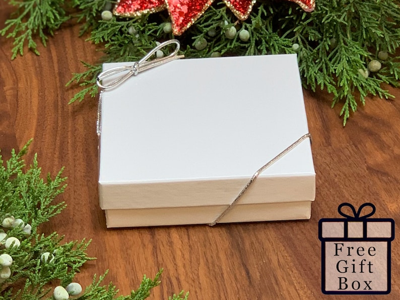 Peut inclure: Une bo&icirc;te cadeau blanche avec un ruban argent&eacute; nou&eacute; en forme de n&oelig;ud. La bo&icirc;te est pos&eacute;e sur une surface en bois. Free Gift Box est &eacute;crit sur une bo&icirc;te cadeau rouge et blanche.