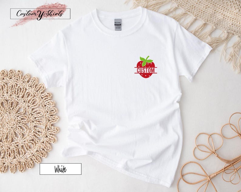 A small graphic on the left chest area, shown on a white short-sleeved t-shirt