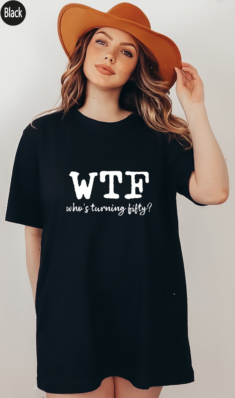 May include: Black oversized t-shirt with white text that reads "WTF who's turning fifty?"