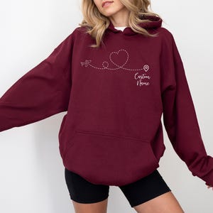 a woman wearing a maroon hoodie with a heart on it