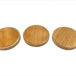May include: Three round wooden coasters with a natural wood finish.