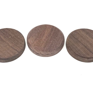 Puede incluir: Tres posavasos redondos de madera de nogal marrón oscuro.