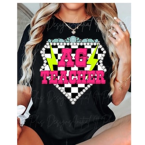 May include: Black t-shirt with a pink and white checkered design. The design features a pink "AG TEACHER" text with yellow lightning bolts on either side.