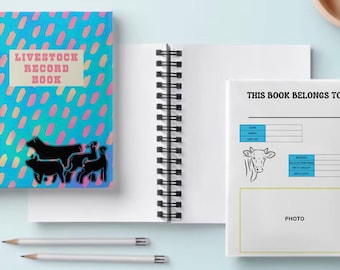 May include: A spiral bound notebook with a colorful cover featuring a pink and blue pattern and the text "Livestock Record Book". The cover also has a black silhouette of a cow, pig, and sheep. The inside of the notebook has a section for recording information about livestock, including name, breed, date of purchase, birth weight, and a space for a photo.