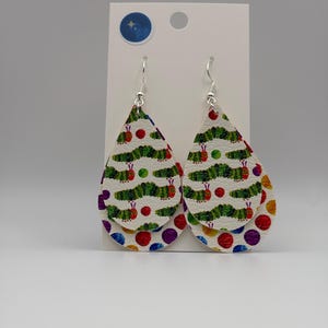May include: A pair of teardrop-shaped earrings featuring a layered design. The top layer displays a repeating pattern of green caterpillars on a white background, while the bottom layer features a colorful polka dot pattern in red, blue, and purple.