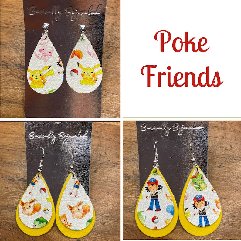 Puede incluir: Un par de pendientes amarillos en forma de l&aacute;grima con fondo blanco y estampado de personaje de Pokemon. Los pendientes est&aacute;n etiquetados como "Beautifully Blinged" y "Poke Friends".