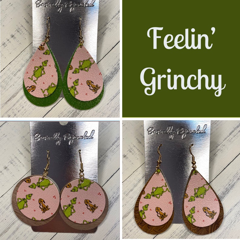 May include: Two pairs of dangle earrings featuring a Grinch pattern on pink and green leather. The earrings are labeled "Beautifully Fringed". The text "Feelin' Grinchy" is displayed on a green background.