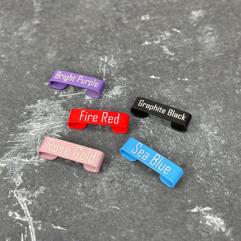 May include: Five metal keyrings in different colours with white text. The colours are bright purple, fire red, rose gold, sea blue, and graphite black. The text on the keyrings reads "Bright Purple", "Fire Red", "Rose Gold", "Sea Blue", and "Graphite Black".
